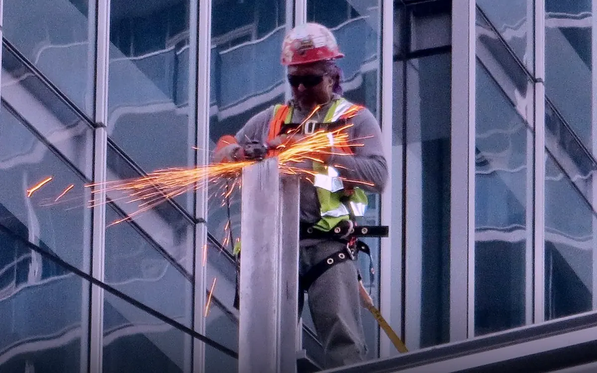 Ouvrier du bâtiment découpant une pièce métallique sur un chantier